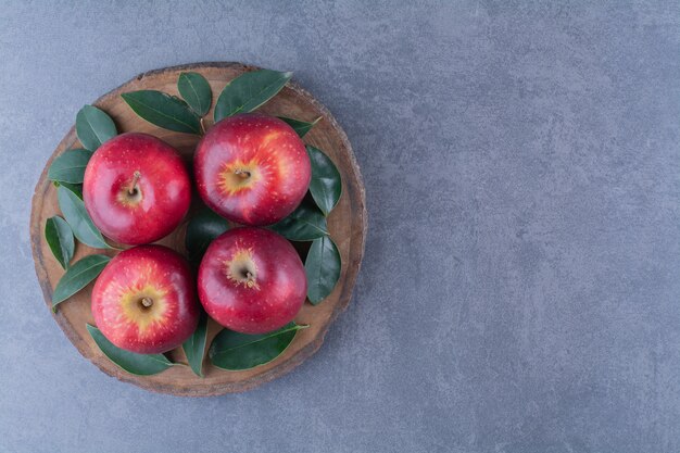 大理石のテーブルのボード上の新鮮なリンゴと葉。