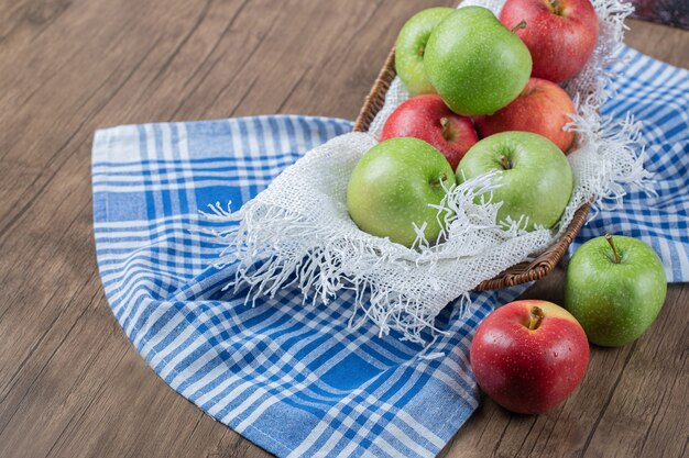 Fresh apples in a metallic basket on a piece of white burlap.