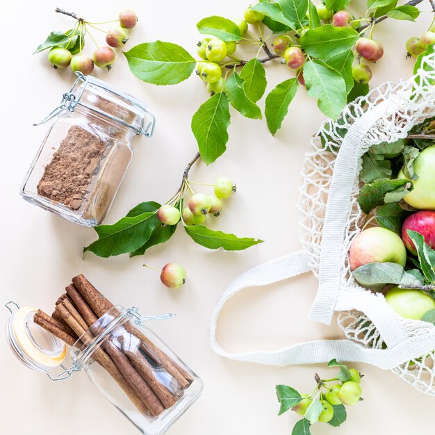 Fresh apples in a shopping mesh bag with branch of apples and cinnamon