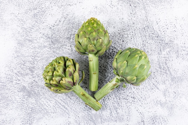 Fresh artichokes on a light gray . top view.