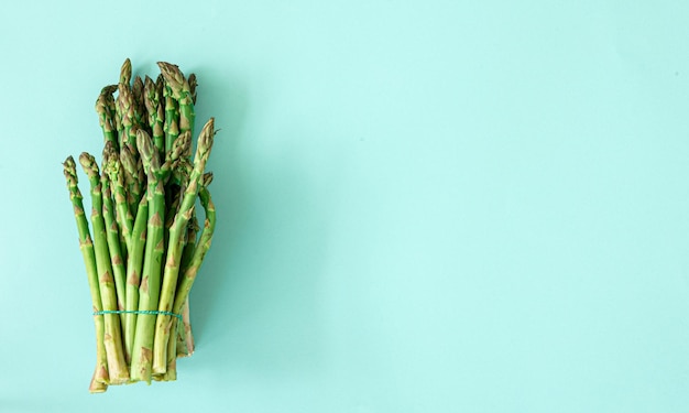 Free photo fresh asparagus plant on blue background flat lay