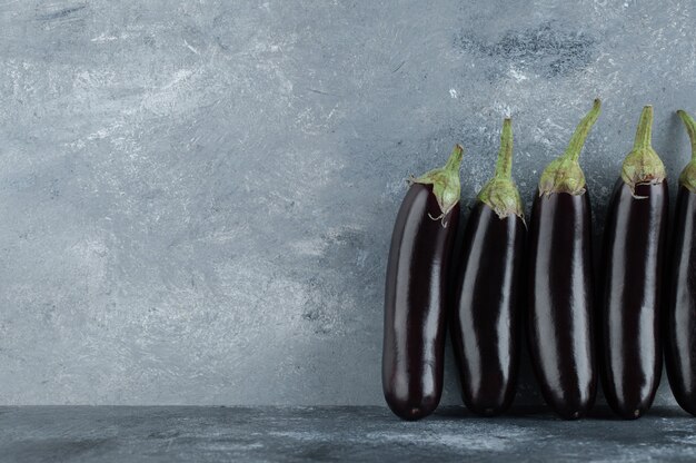 Fresh aubergine row on grey background.