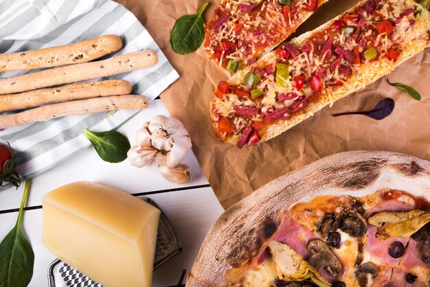 신선한 바게트 피자; 치즈 블록; 가는 사람; 빵 스틱; 테이블에 마늘 화이트 피자