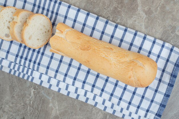 Fresh baguette slices on blue tablecloth. High quality photo