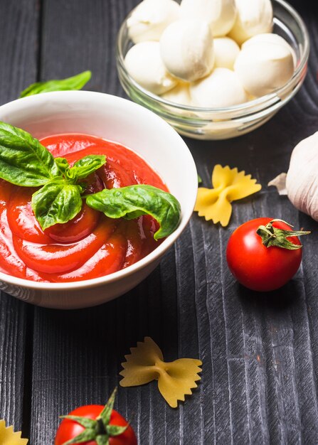 Fresh basil on red tomato sauce in the bowl with farfalle pasta and mozzarella