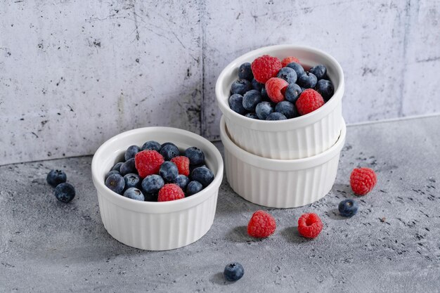 Fresh berries in small bowls on grey