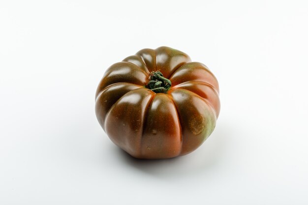 Fresh black tomato on a white wall. .