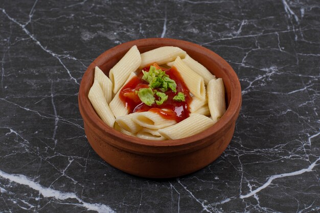 Fresh boiled penne pasta with ketchup in bowl.