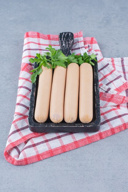 Fresh boiled sausage on black cutting board. 