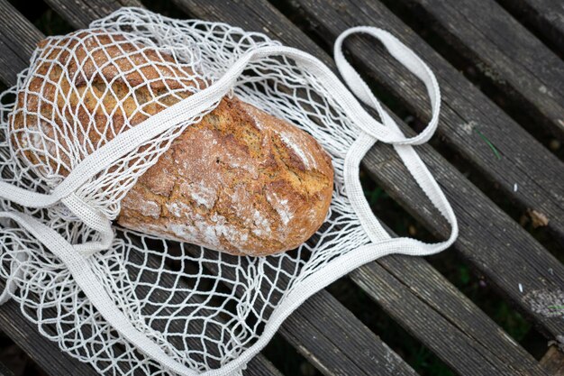 Fresh bread in a shopping bag on a wooden background
