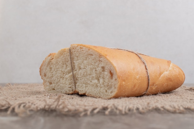 Свежий хлеб, перевязанный веревкой на мраморе. Фото высокого качества