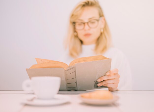 Fresh breakfast in front of defocussed young businesswoman reading the book