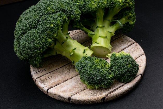 Fresh broccoli on cutting board on black surface