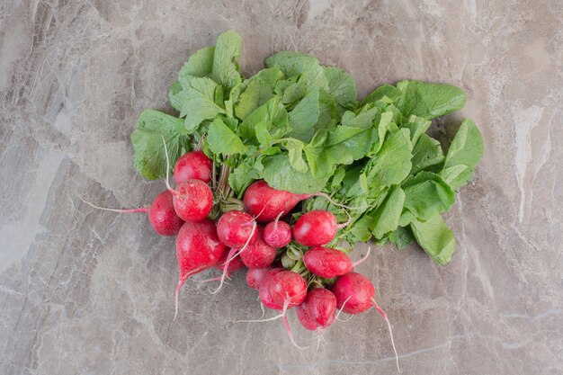 Fresh bunch of red turnips and turnip leaves on marble.