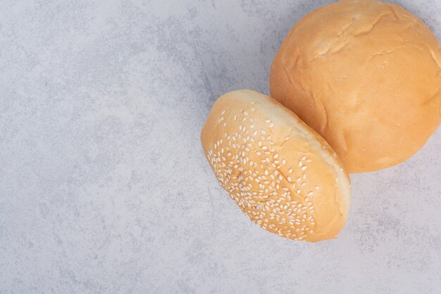 Fresh buns with sesame seeds on stone surface