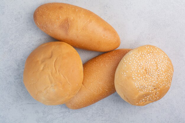 Fresh buns with sesame seeds on stone surface