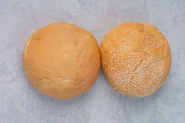 Fresh buns with sesame seeds on stone surface