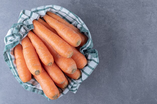 Fresh carrots on towel in the bowl , on the marble surface.