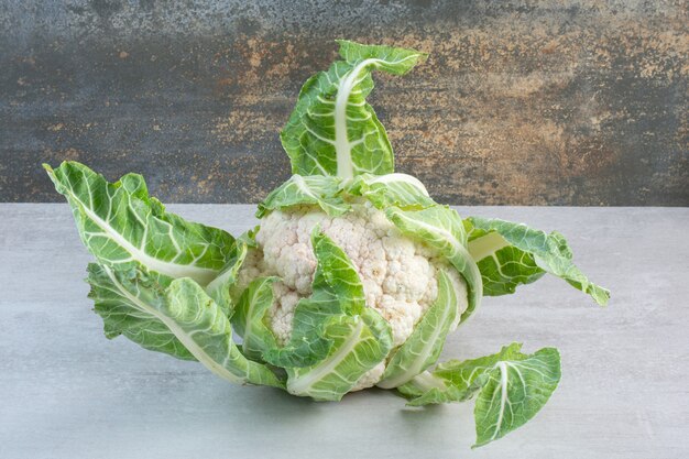Fresh cauliflower with leaves on stone table. High quality photo