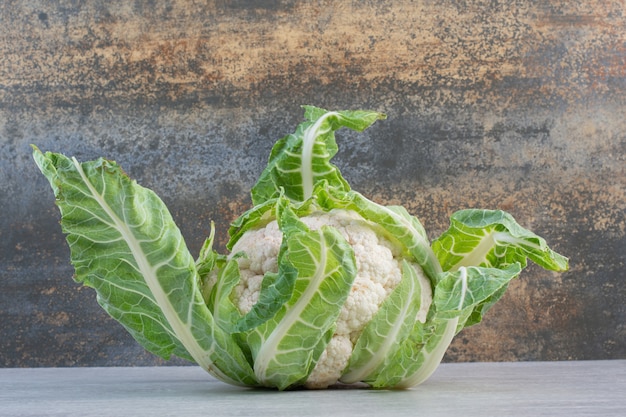 Fresh cauliflower with leaves on stone table. High quality photo