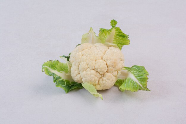 Fresh cauliflower with leaves on white.