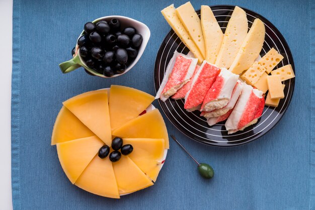 Fresh cheese and snacks near olives on plates