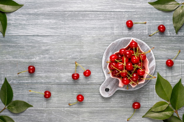 Free photo fresh cherry on plate on grey table top view