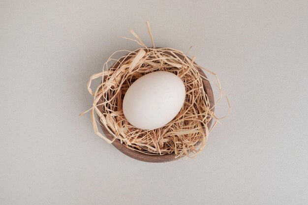 Fresh chicken white egg with hay in wooden bowl.