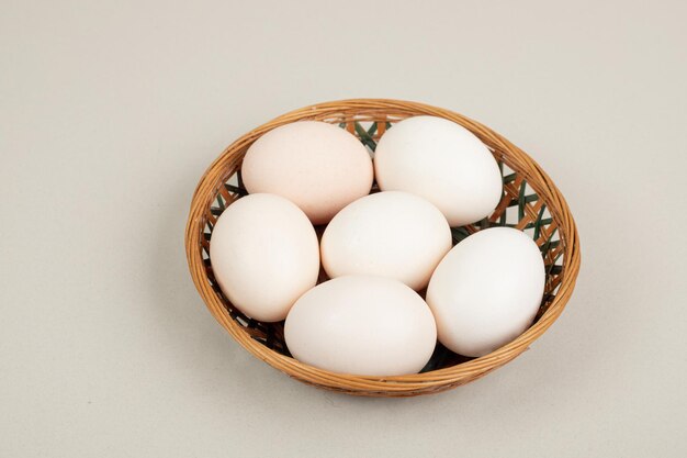 Fresh chicken white eggs on wicker basket .