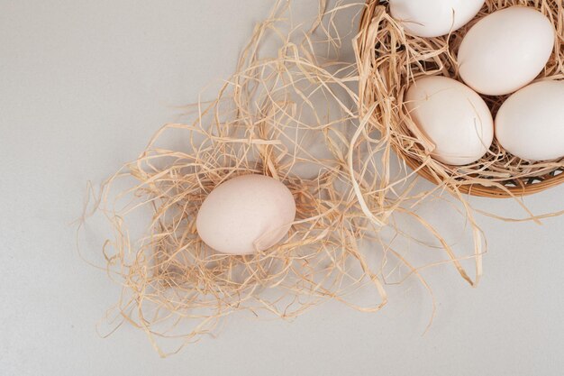 Fresh chicken white eggs on wicker basket .