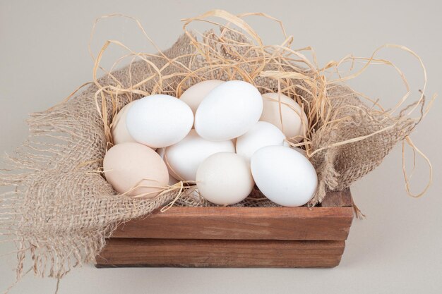 나무 바구니에 건초와 신선한 닭고기 흰 계란.