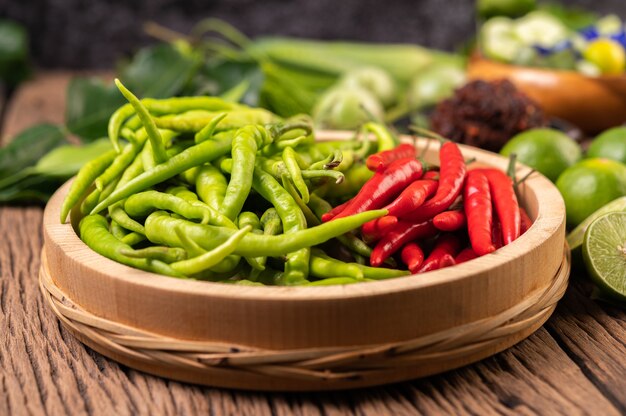 Fresh chili on a wooden tray with lemon and kaffir lime leaves.