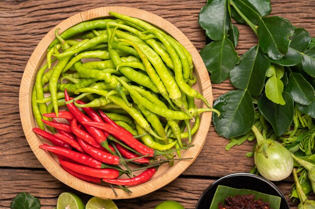 Fresh chili on a wooden tray with lemon and kaffir lime leaves.