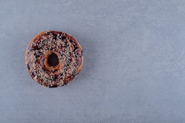 Свежий шоколадный пончик на серой поверхности. Вид сверху
