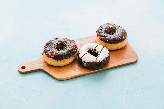 Fresh chocolate donuts on chopping board