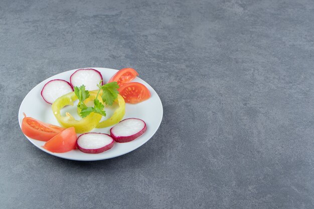 Свежие нарезанные овощи на белой тарелке.