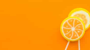 Free photo fresh citrus fruit lollipops on orange backdrop