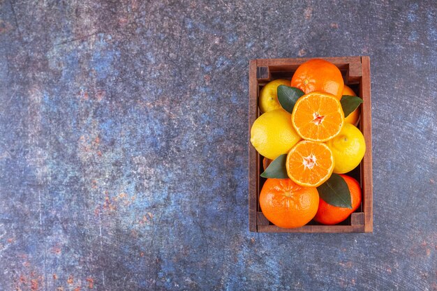 木製の古い箱に置かれた葉を持つ新鮮な柑橘系の果物。