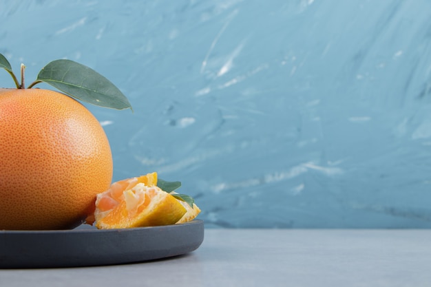 Fresh clementine and segments on black cutting board. 