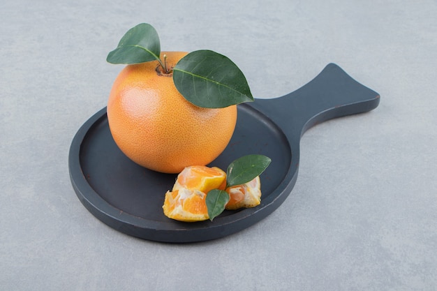 Fresh clementine and segments on black cutting board