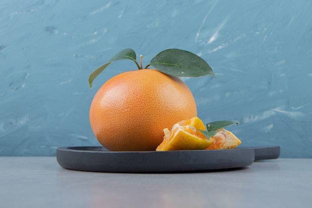 Free photo fresh clementine and segments on black cutting board