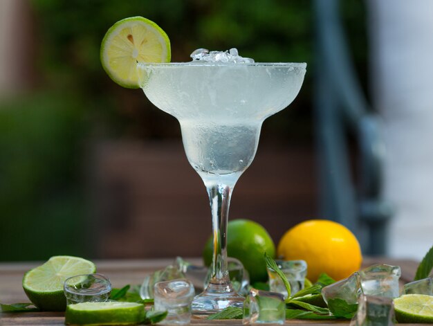 Fresh cocktail drink with alcohol, ice cubes and a slice of lime in a glass