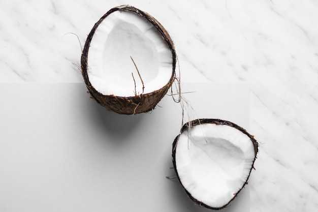 Free photo fresh coconut cut in half on white and marble backdrop