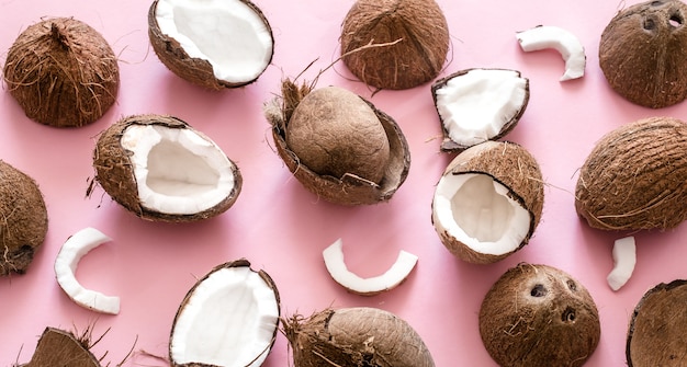 Fresh coconut halves on a pink background, pop art design. Top view, close-up, creative concept