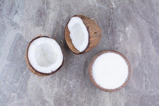 신선한 코코넛과 돌 표면에 설탕 그릇.