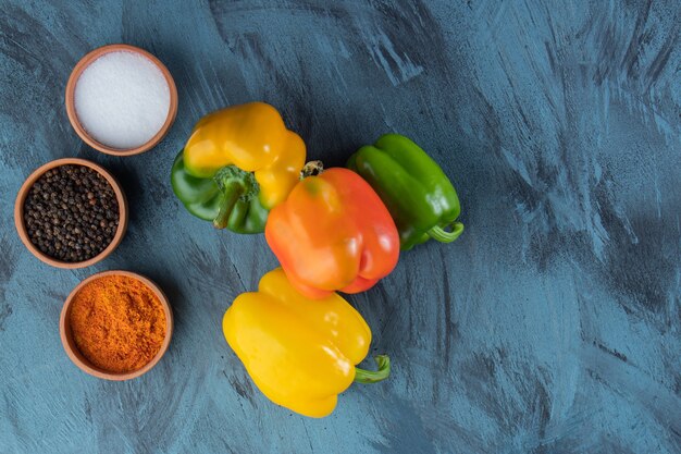 Fresh colorful organic peppers and condiments on blue surface.