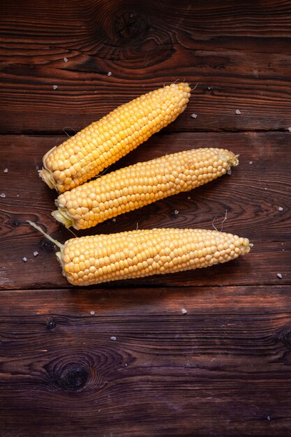 Fresh corn on a dark wooden table. top view.