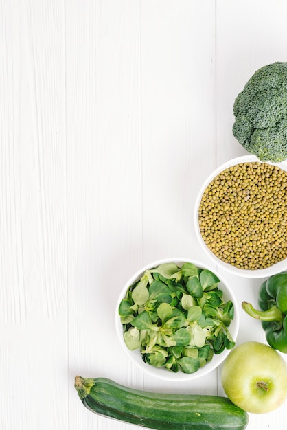 Fresh corn salad leaves; apple; broccoli; cucumber and mung beans on white desk