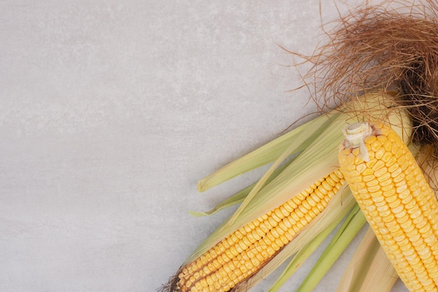 Free photo fresh corns on cobs on white table.