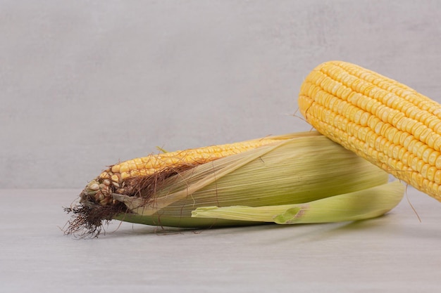 Fresh corns on cobs on white table.